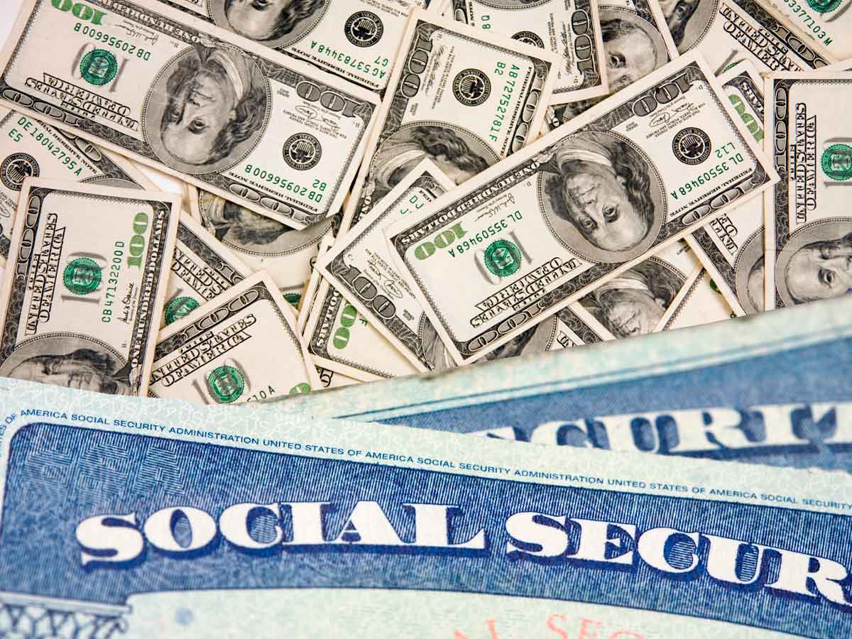 Pile of 100-dollar bills and a Social Security card illustrating benefit payments due May 14 and May 28 for eligible retirees