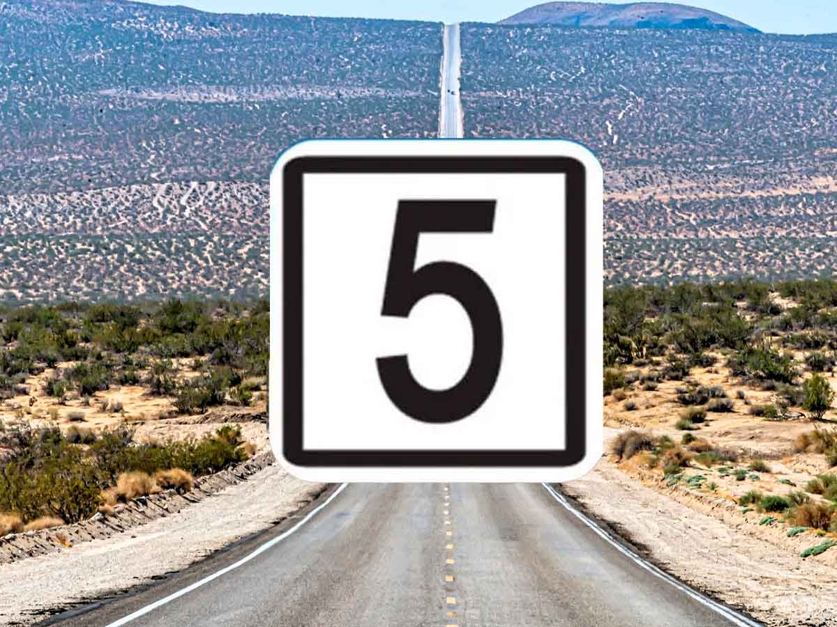 White road sign displaying black number 5, marking kilometer 5 on a long desert highway in the United States