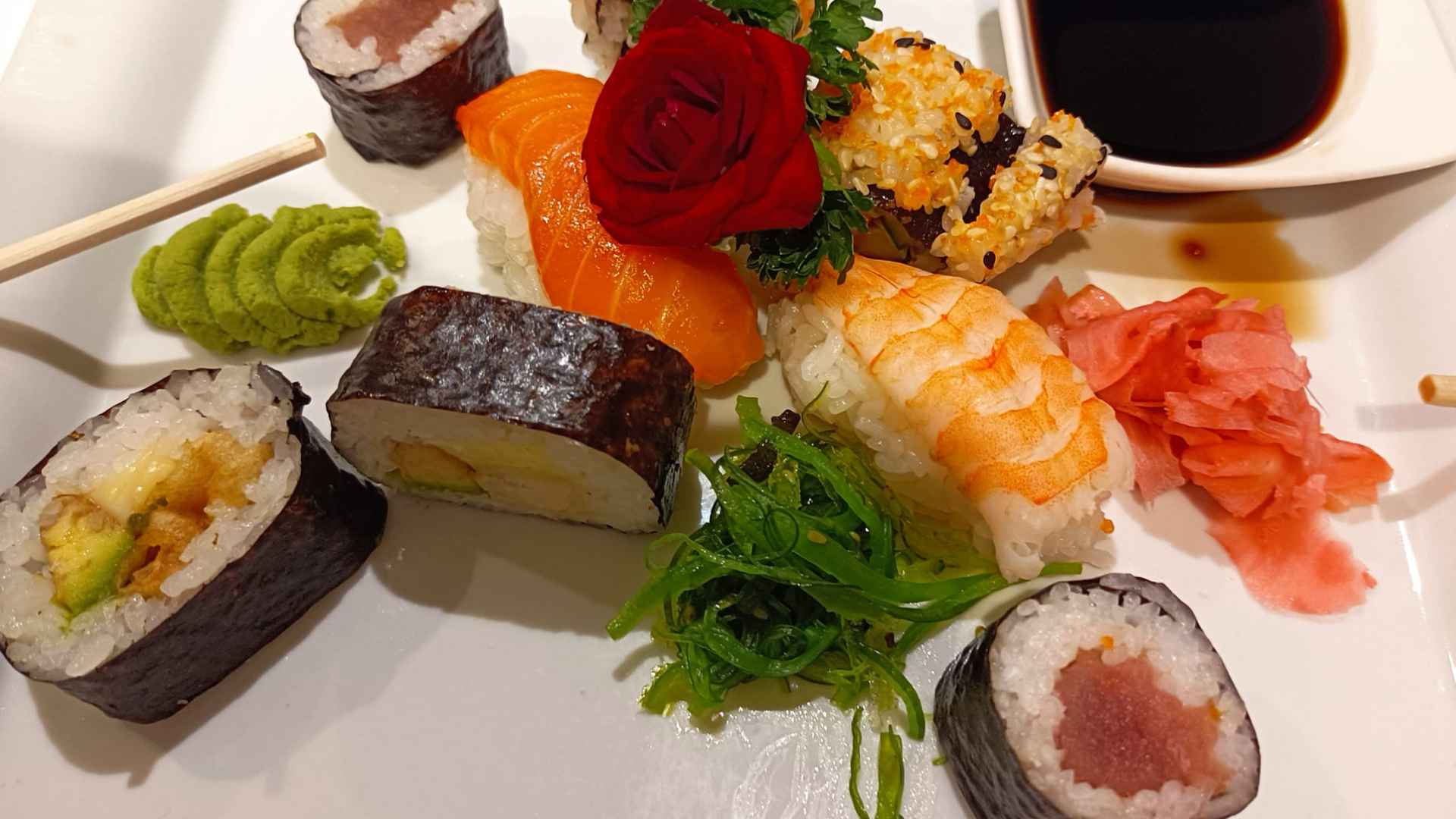 Assorted sushi platter with salmon and shrimp nigiri, signature Morristown Roll, seaweed salad, wasabi, and pickled ginger at Laku Sushi.