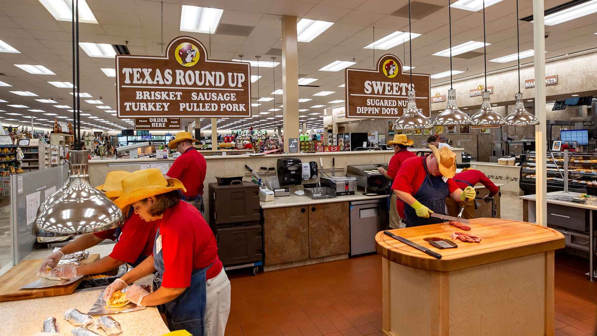 Buc-ee’s employees carving brisket and sausage at the Texas Round Up food counter inside a brightly lit new store location.