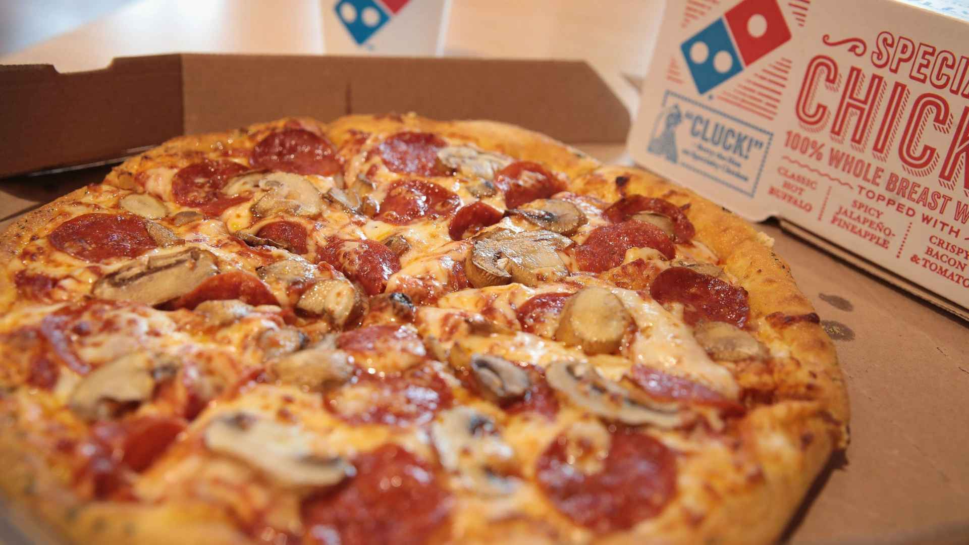 Close-up of Domino’s pepperoni-mushroom pizza in a delivery box as the chain prepares to close 205 underperforming stores.