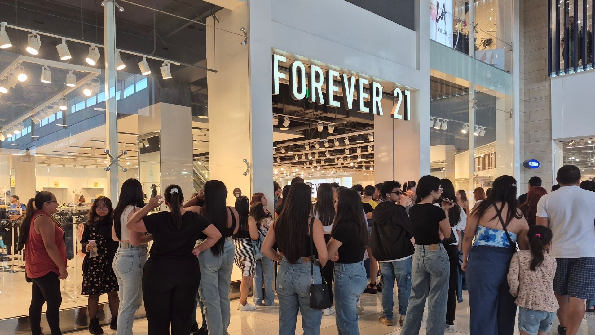 Customers wait outside a Forever 21 store in a shopping mall following the announcement that the company is closing its 354 stores in the United States due to bankruptcy.
