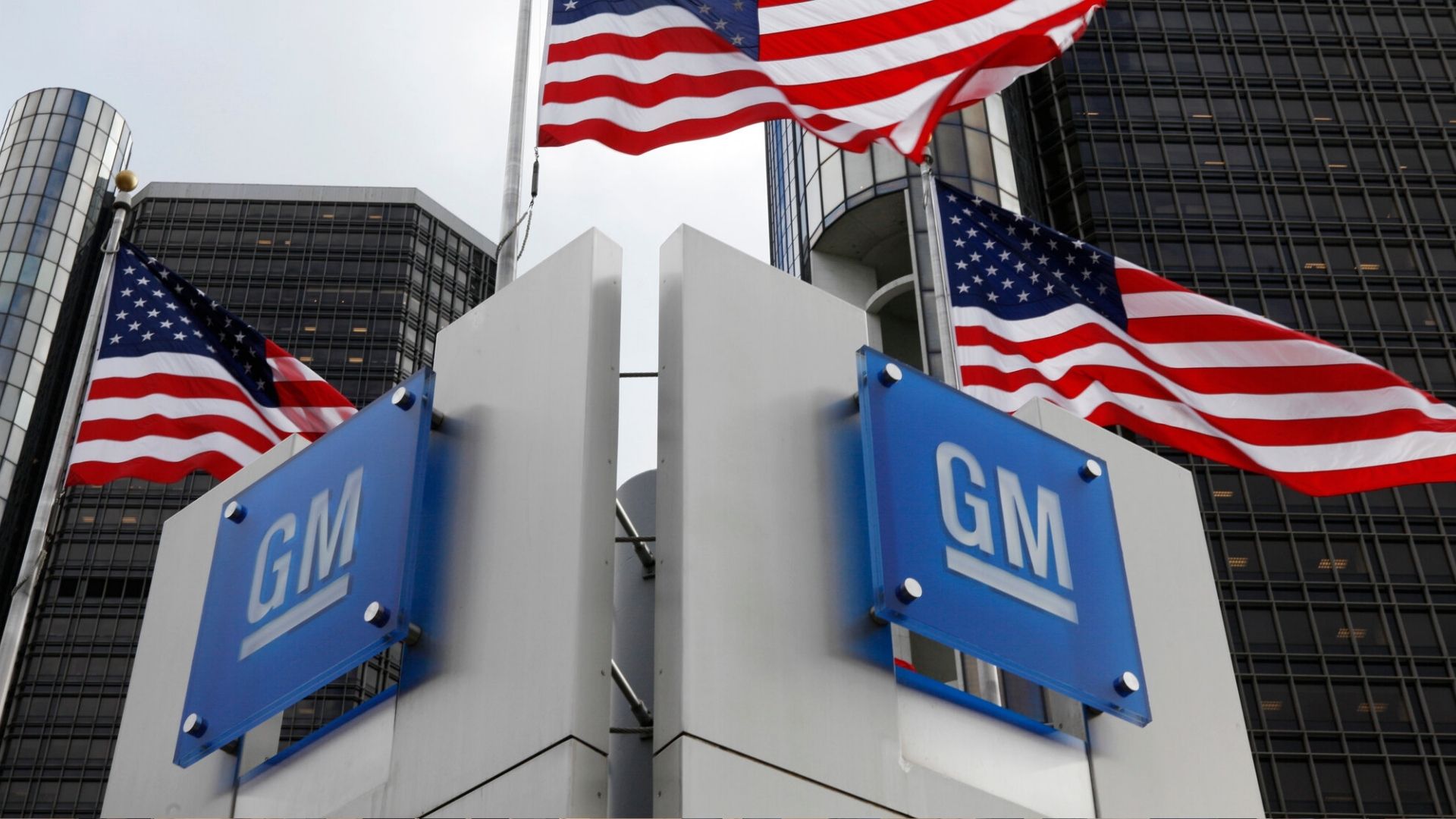 GM logo at Detroit headquarters with American flags, symbolizing the end of Chevy Malibu production and 2,000 Fairfax layoffs amid electric shift