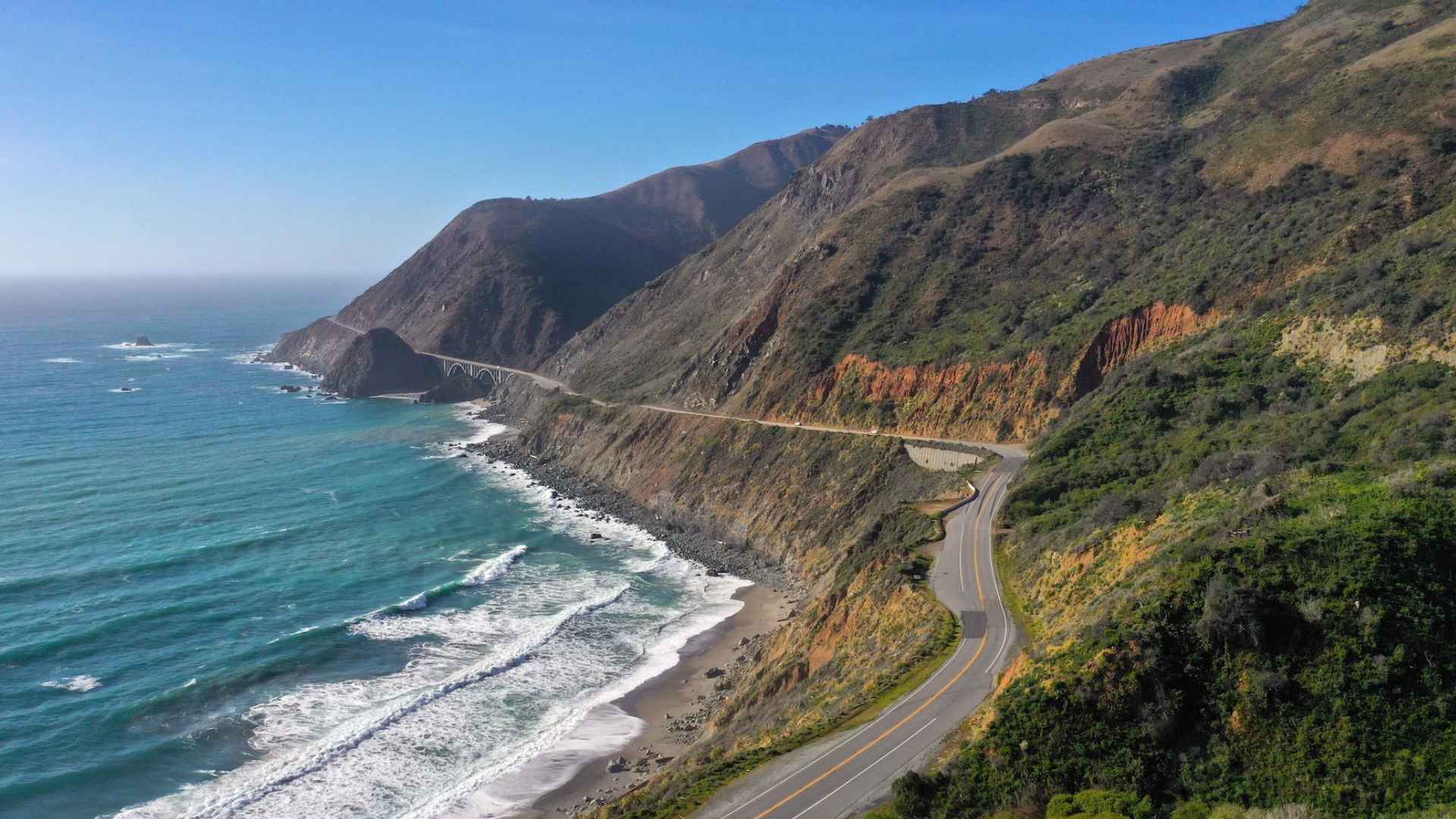Aerial view of Highway 1 winding along Big Sur’s cliffs near Regent’s Slide, a stretch closed until summer 2025 for landslide repairs
