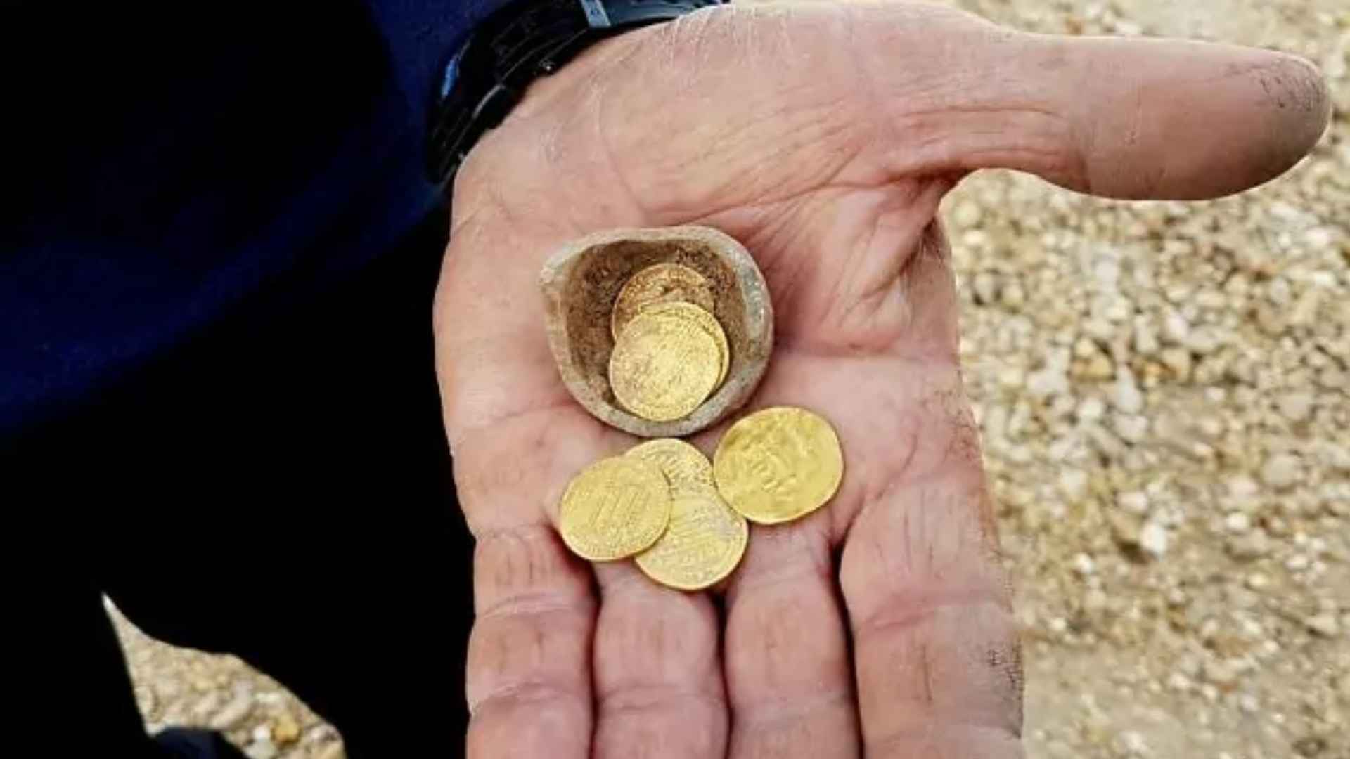 Close-up of a hiker’s hand holding World War II–era gold coins unearthed in the Czech Republic’s Giant Mountains