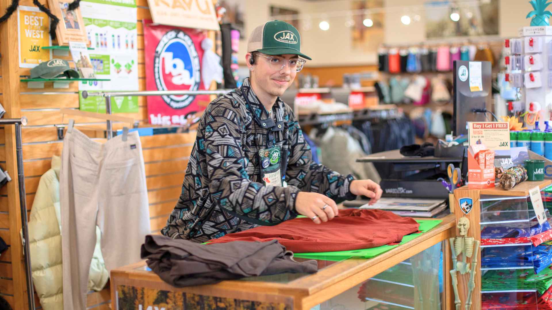Jax Ames Outdoor Gear employee folding clothes during liquidation sale before the 70-year-old store closes this summer.