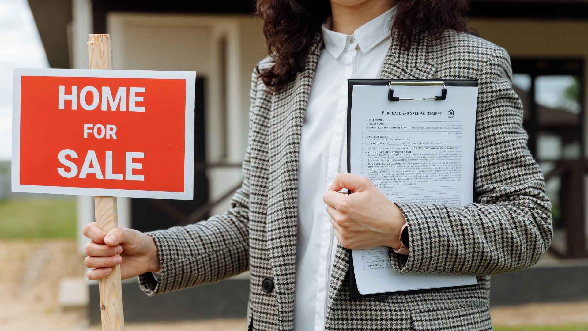 Real estate agent holding red “home for sale” sign and purchase agreement, symbolizing buyer hopes for 4 percent mortgage rates