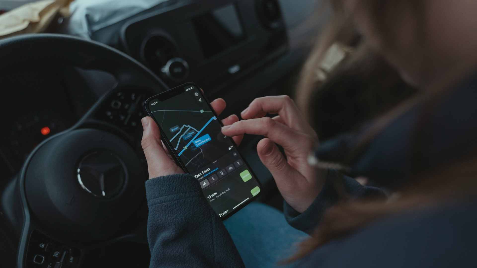 Driver using smartphone navigation behind steering wheel, illustrating distracted driving targeted by Pennsylvania's Paul Miller’s Law phone ban.