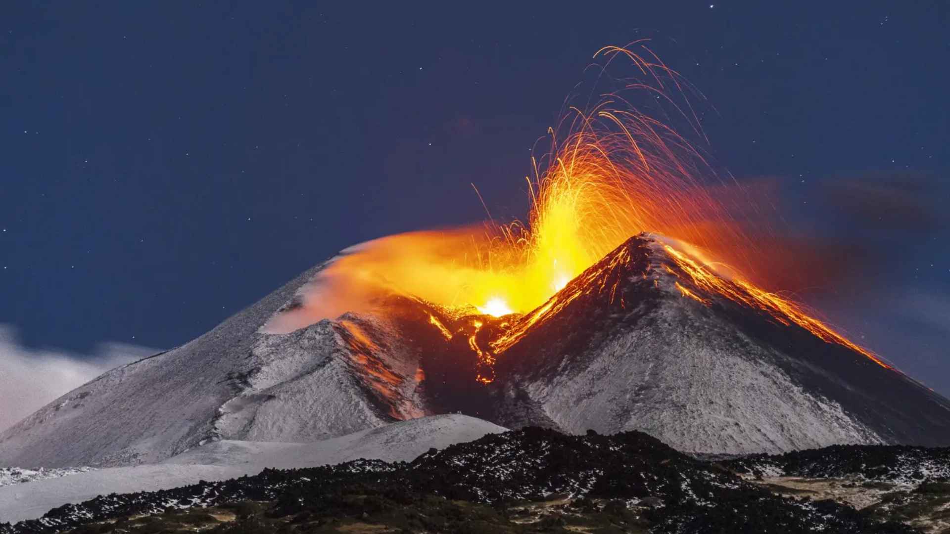 Volcano erupting at night with glowing magma jets, illustrating sulfur-rich magma pathway that lifts gold from Earth’s mantle.