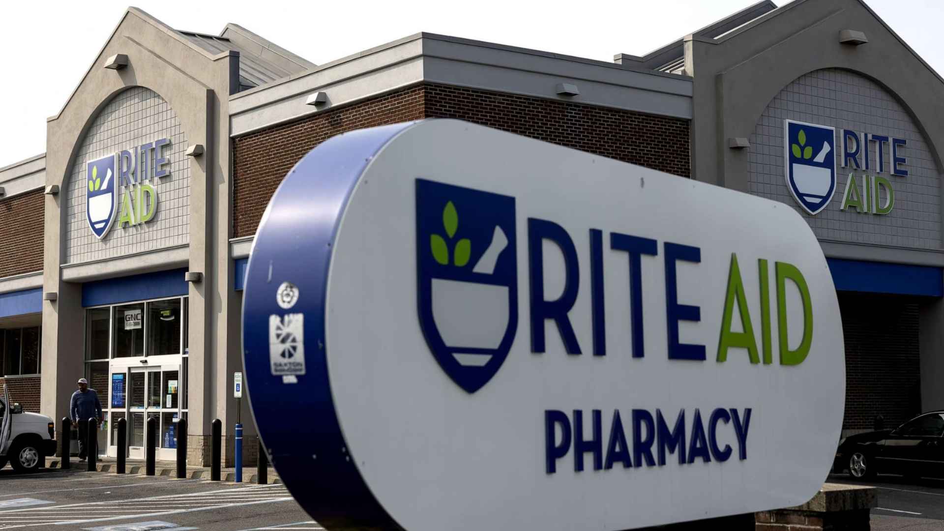 Exterior of a Rite Aid pharmacy with a prominent blue-and-green logo sign, illustrating the chain’s second bankruptcy and looming store closures.