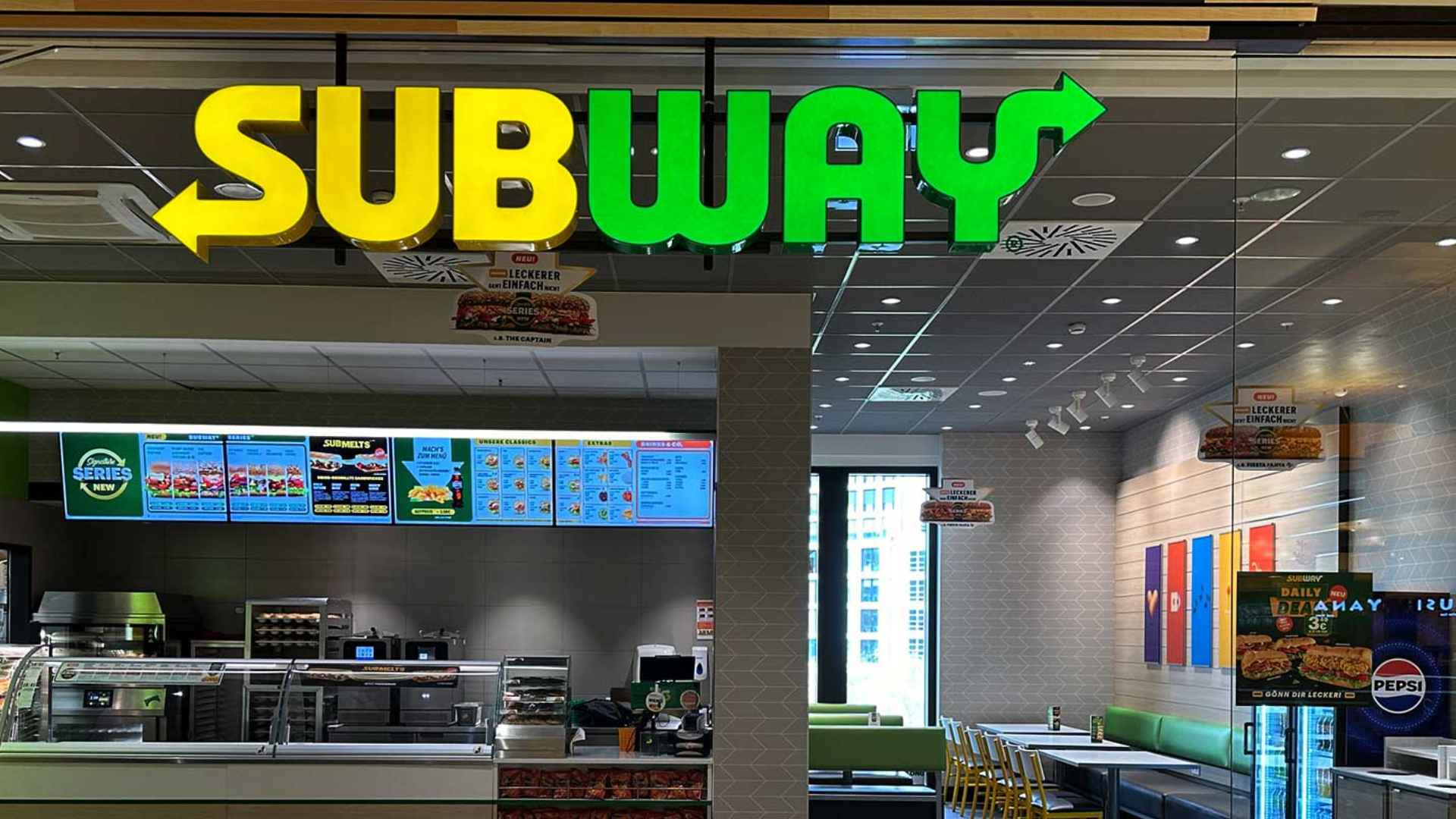 Empty Subway restaurant interior with illuminated logo, illustrating chain’s closure of 630 U.S. stores amid 20-year crisis.