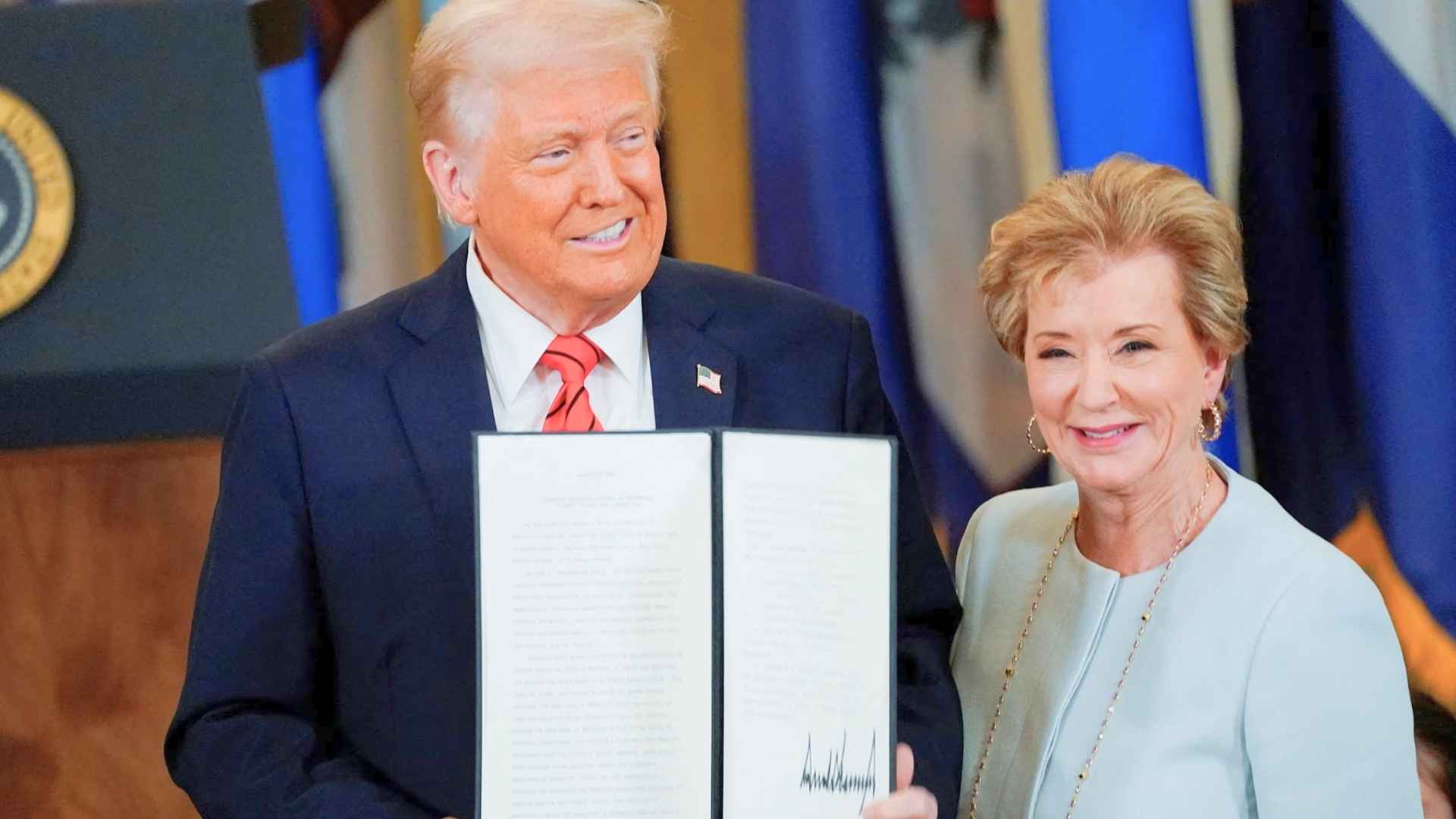 President Donald Trump and Education Secretary Linda McMahon display signed executive orders in the Oval Office