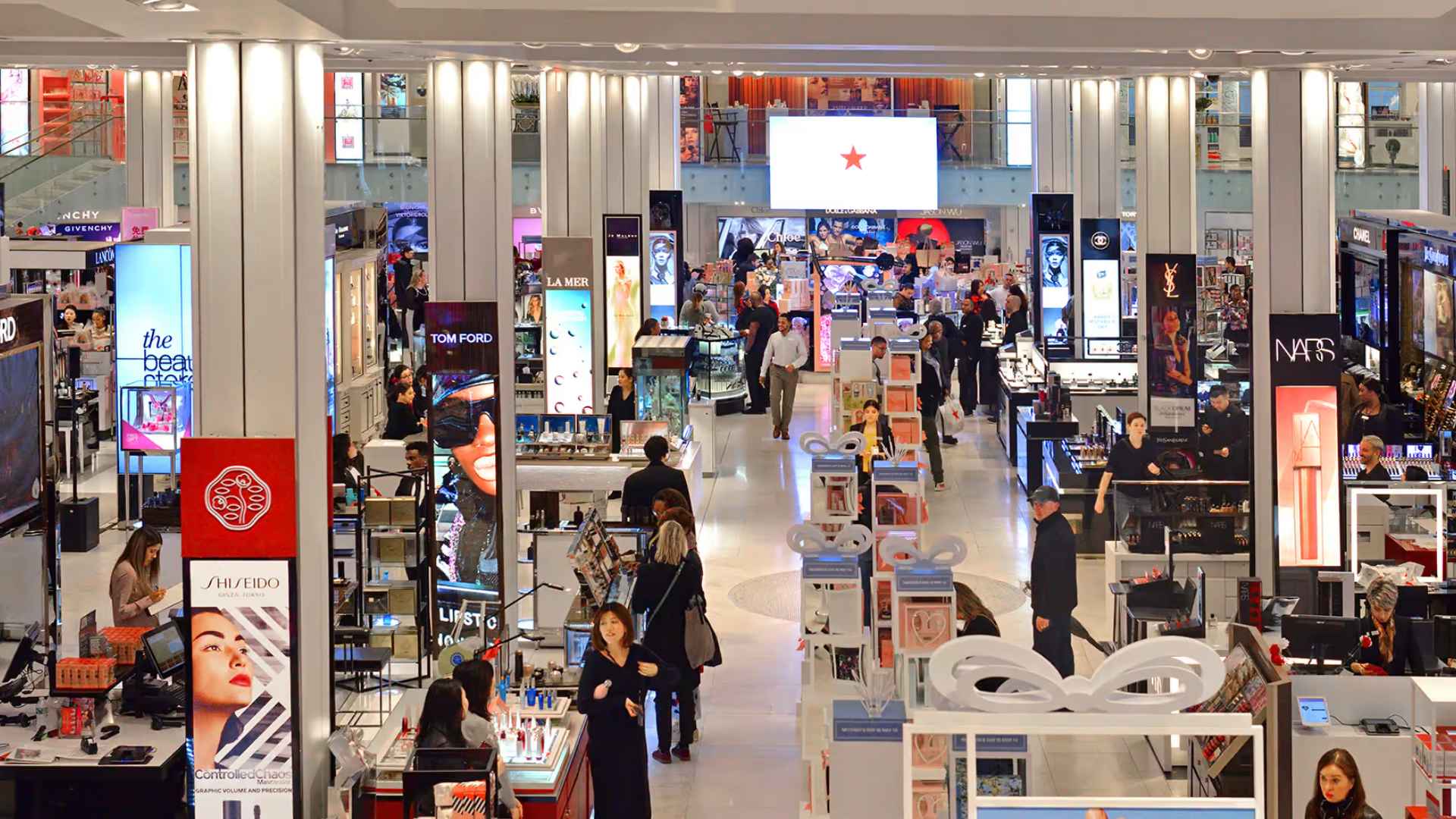 Busy beauty department at Macy’s flagship store, shoppers sampling cosmetics amid the chain’s reinvention after closing 100-plus locations.