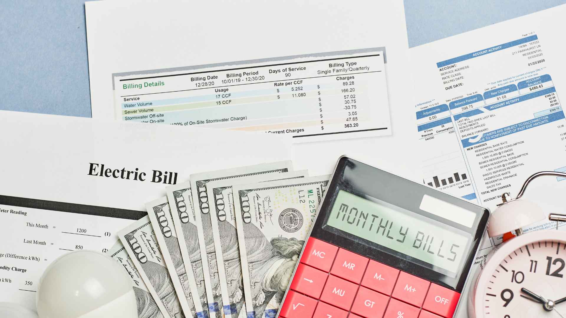 Electric bill statement with cash, calculator showing monthly bills, and utility documents on a desk