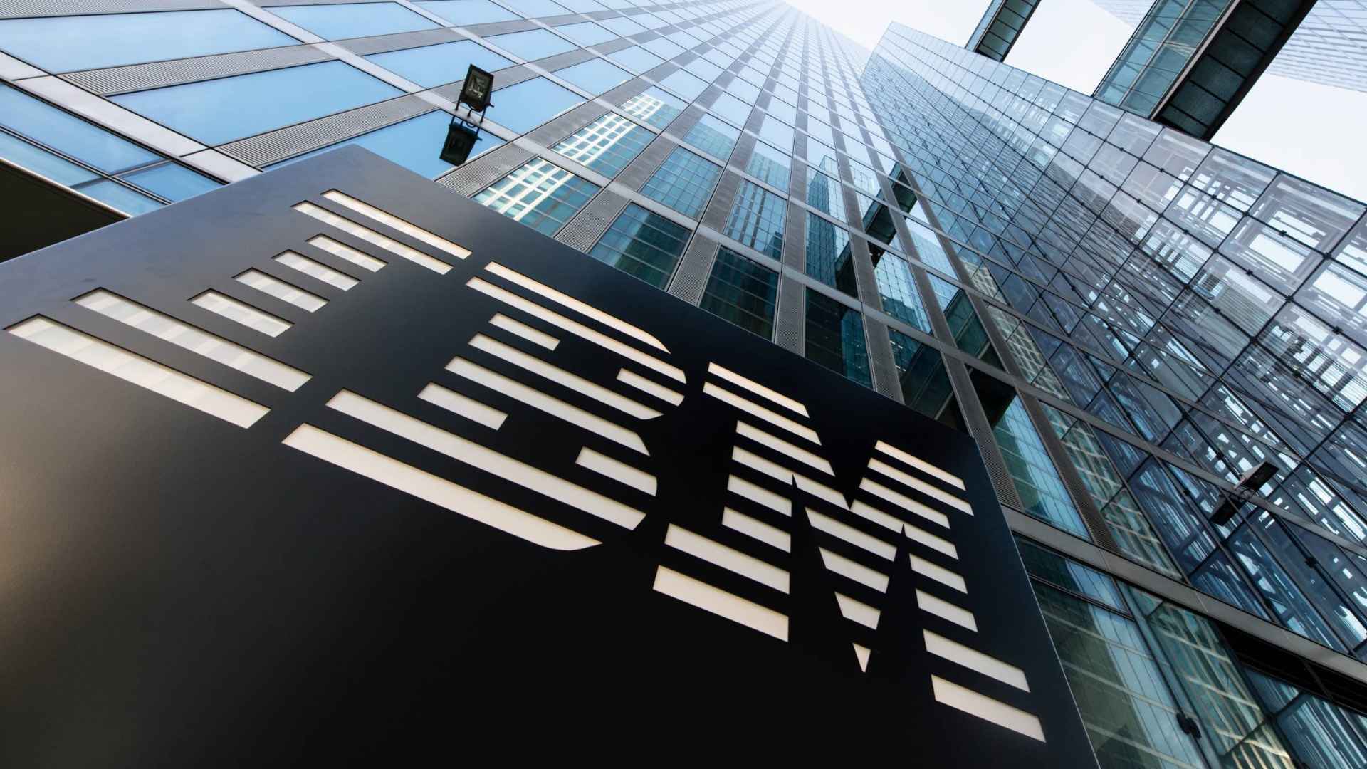 IBM logo outside glass headquarters building, illustrating company layoffs of 8,000 HR employees replaced by AI