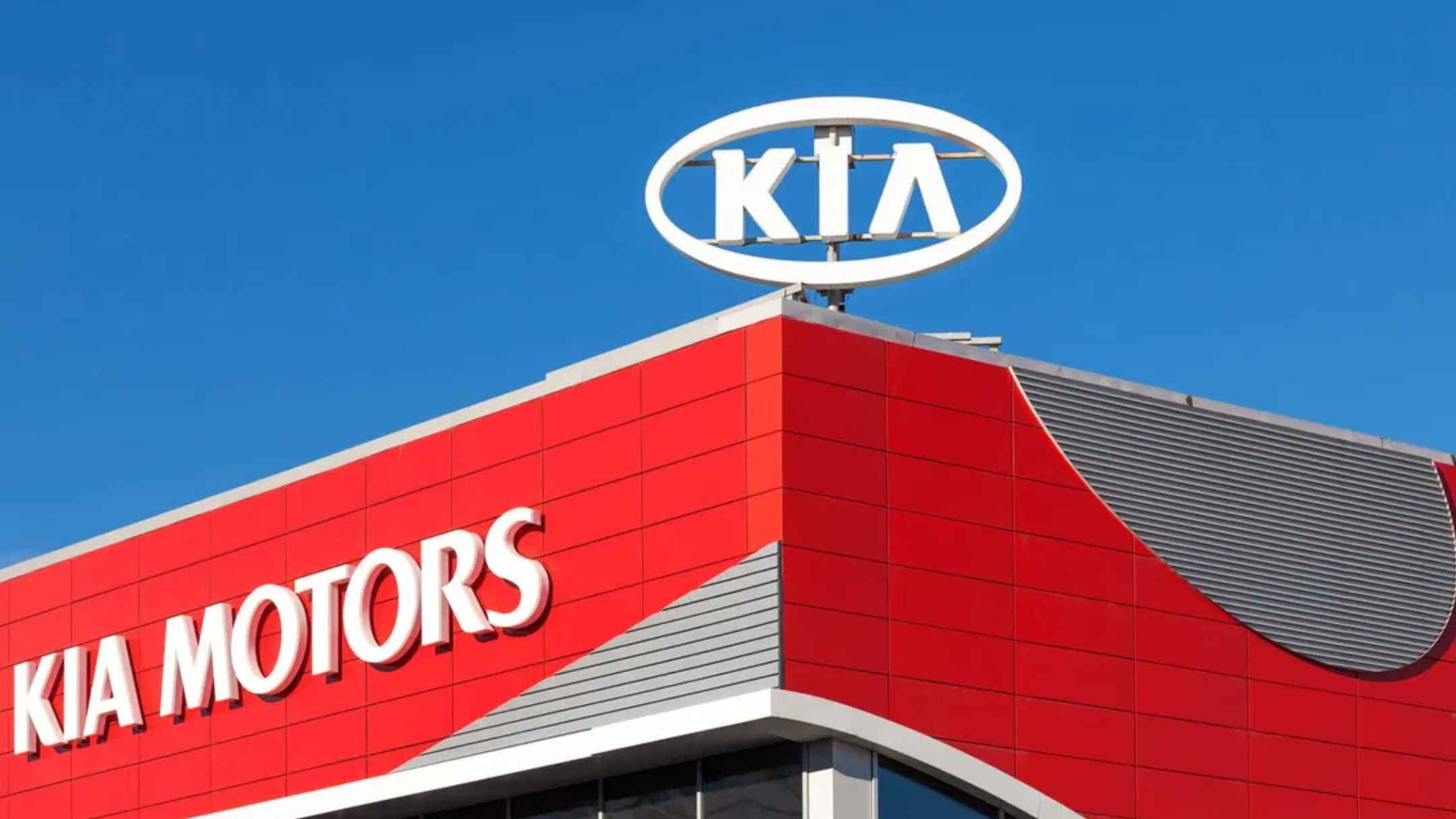 Red Kia Motors dealership with large rooftop logo under clear blue sky amid nationwide recall of 82,000 vehicles.