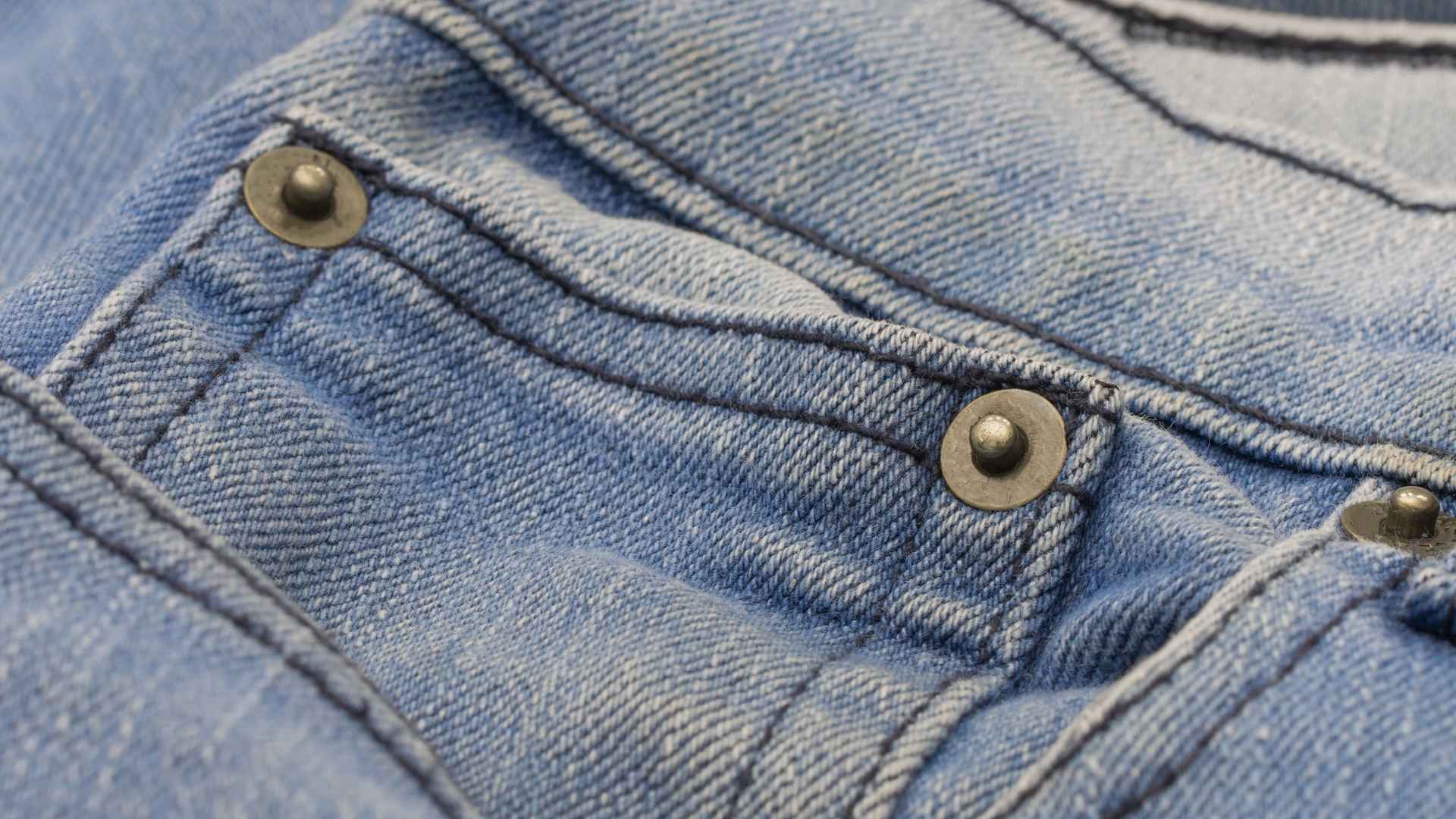 Close-up of copper rivets reinforcing a blue denim pocket, illustrating Levi’s historic solution for tear-resistant jeans.