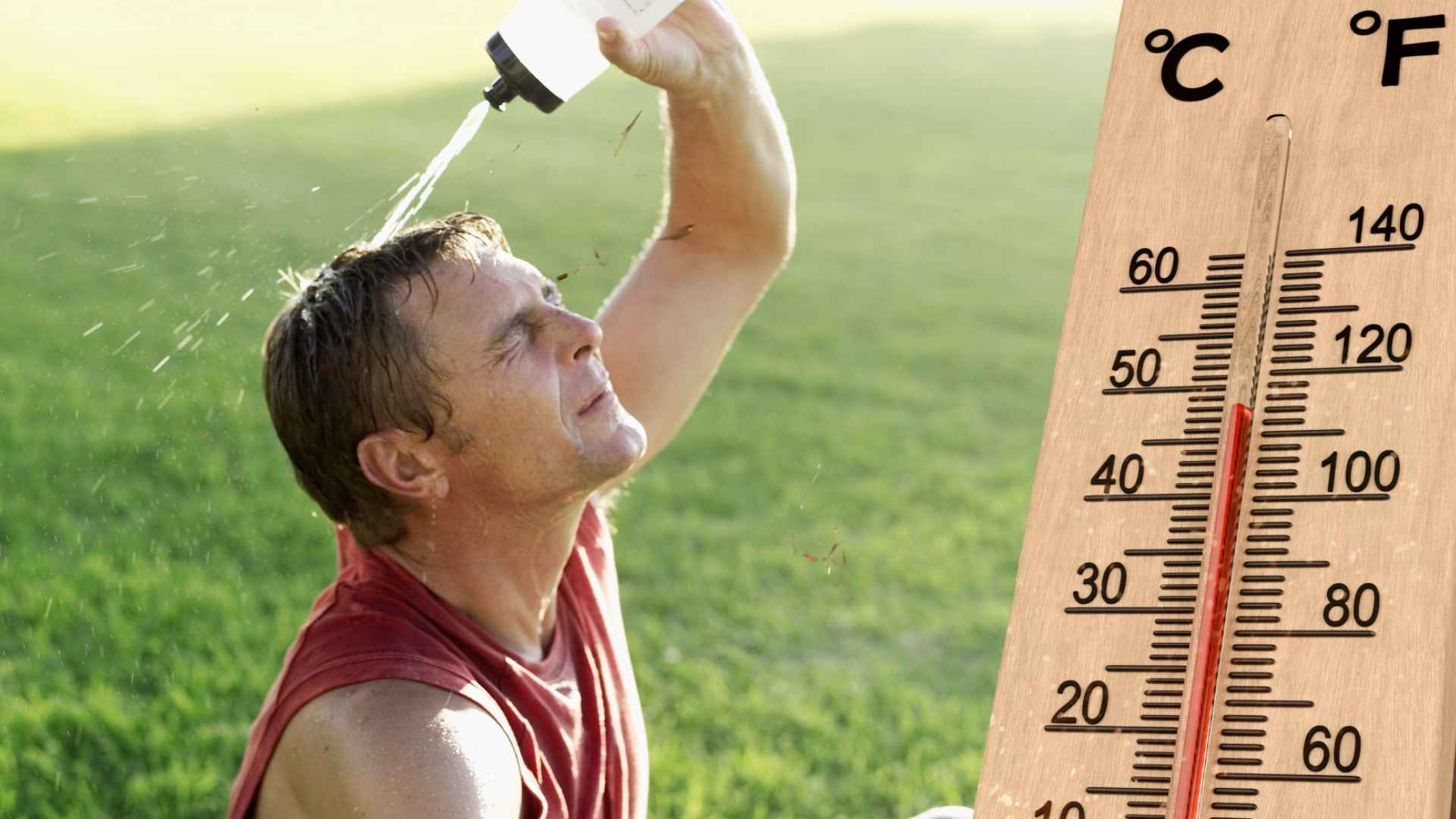 Man pours water over his head beside a thermometer reading nearly 100 °F during NOAA and NWS-warned U.S. heat wave.