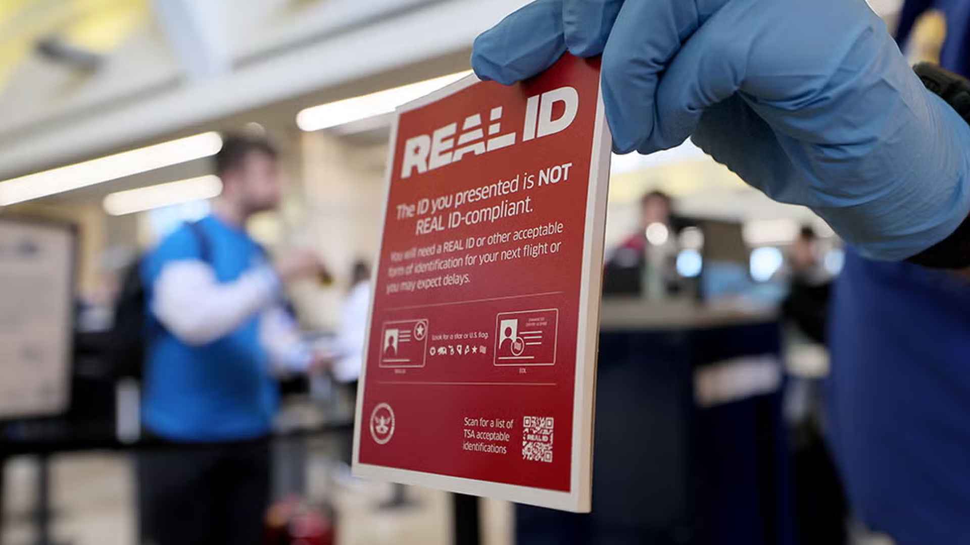 TSA officer holds a notice warning travelers about non-compliant Real ID at a U.S. airport security checkpoint