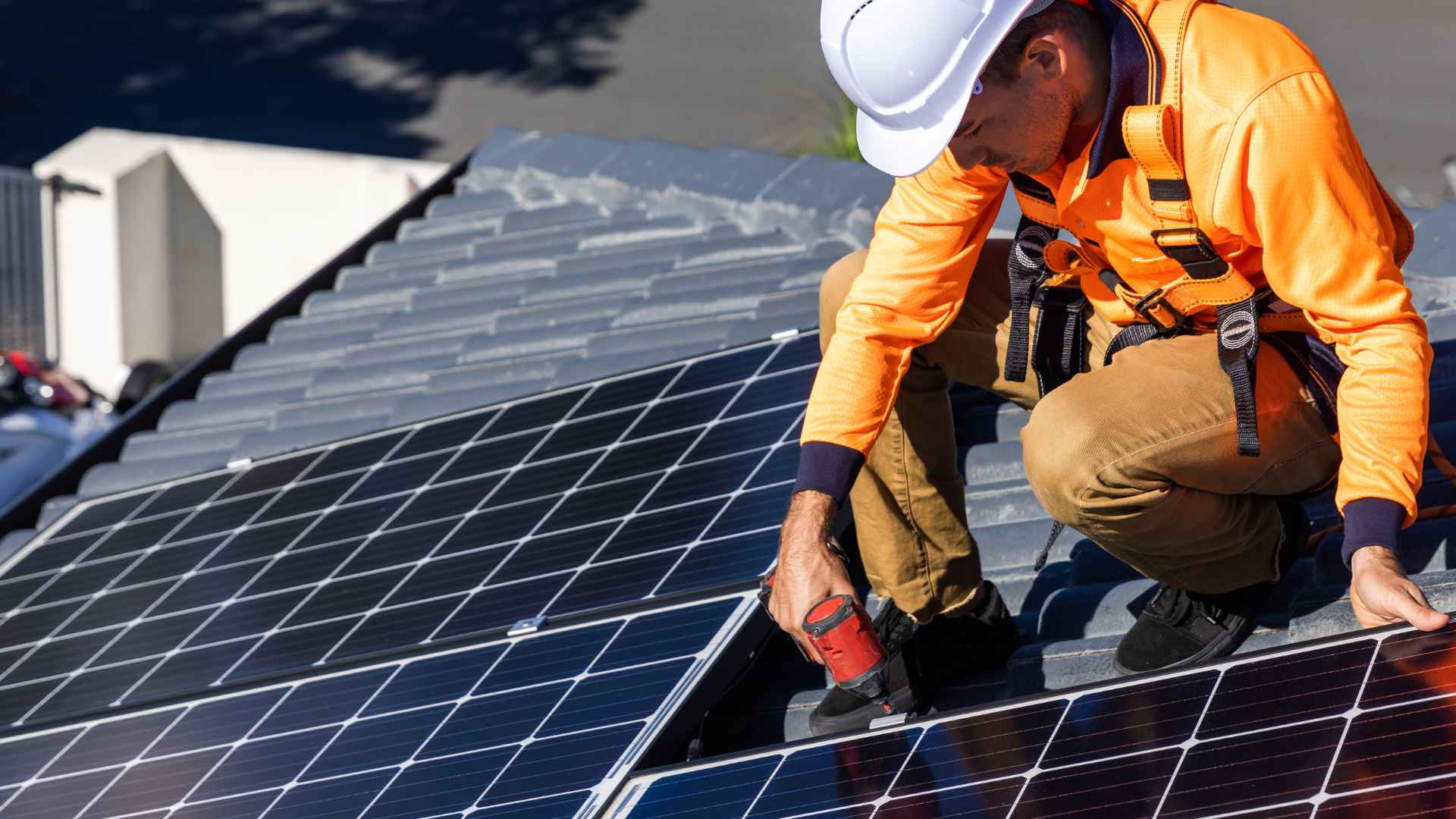 Rooftop technician in safety gear installing silicon solar panels, illustrating today’s standard photovoltaic technology