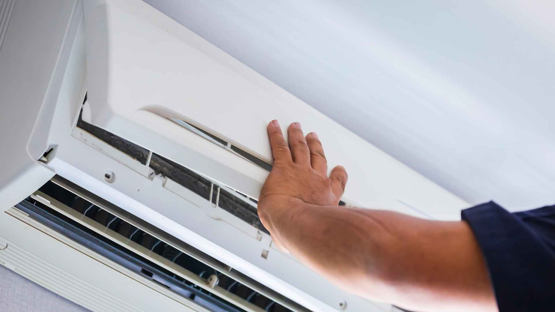 Hand checking indoor split-AC panel before thermometer test to detect low refrigerant gas