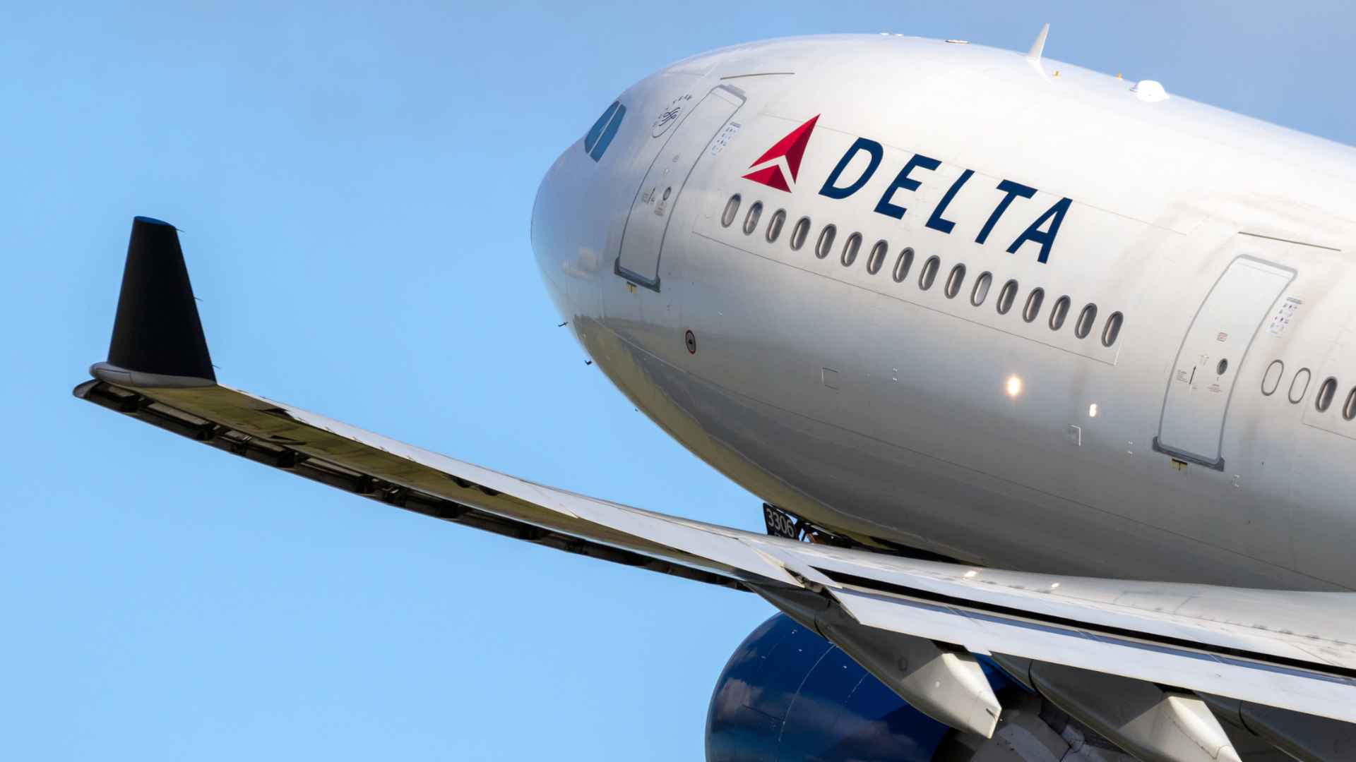lose-up of a Delta Air Lines airplane flying against clear blue sky