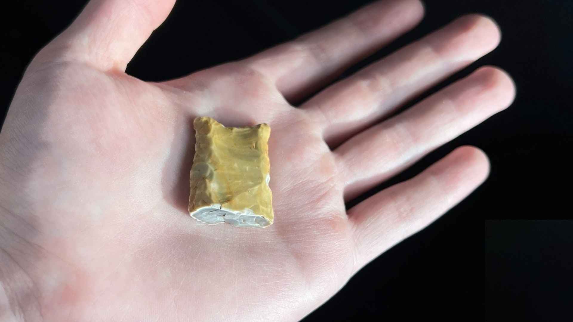 Hand holding a broken Clovis point artifact found on the beach of the Bolivar Peninsula, estimated to be 12,000 years old