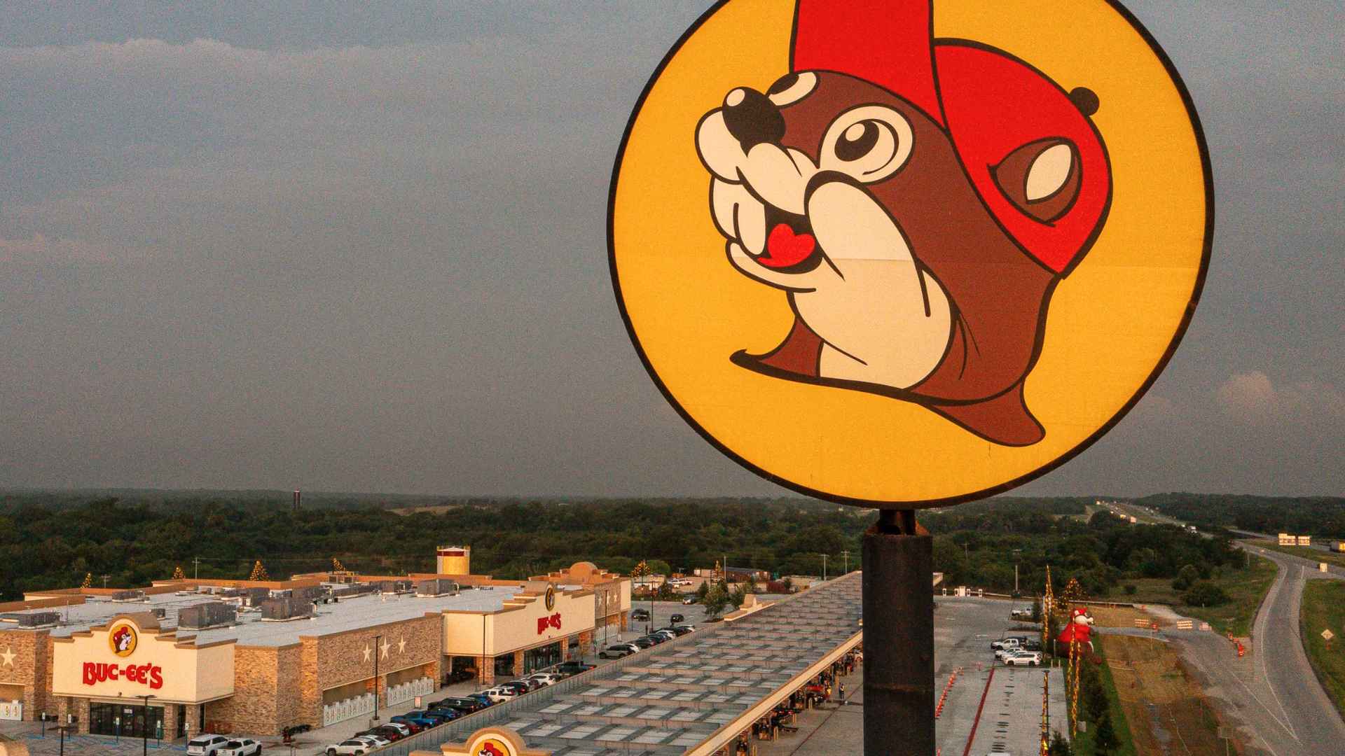 Buc-ee’s beaver logo sign above sprawling travel center, gas pumps and highway, illustrating the chain’s planned 2025-2027 expansion.