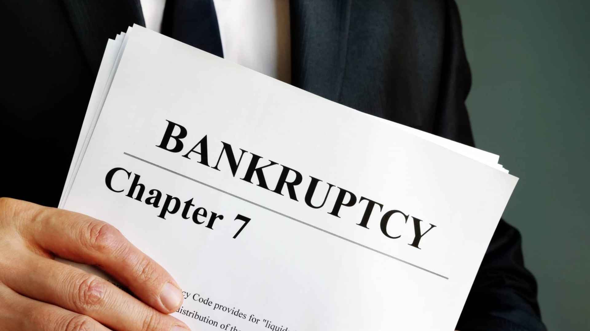Businessman holding Chapter 7 bankruptcy document amid financial scandal