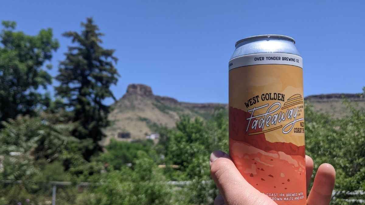Can of West Golden Fadeaway IPA from Over Yonder Brewing with a mountain backdrop in Golden, Colorado.