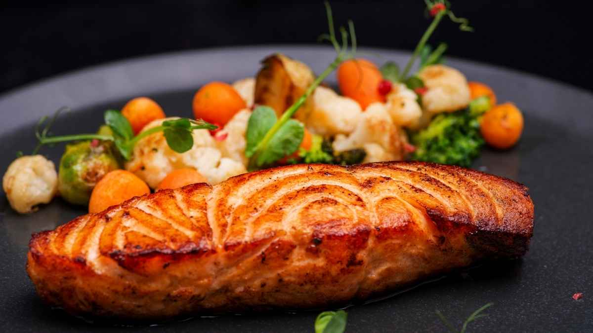 Plate of lab-grown salmon served with colorful vegetables, a part of the new sustainable seafood trend