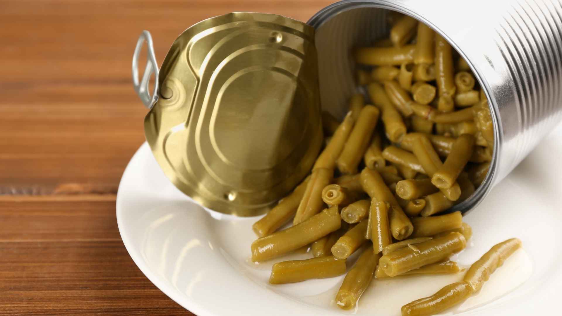 Open can of green beans on a white plate, subject of FDA product recall due to contamination risk