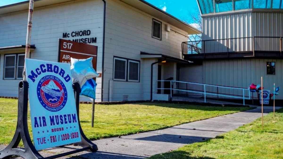 Exterior view of McChord Air Museum with a sign showing museum hours and blue balloons outside
