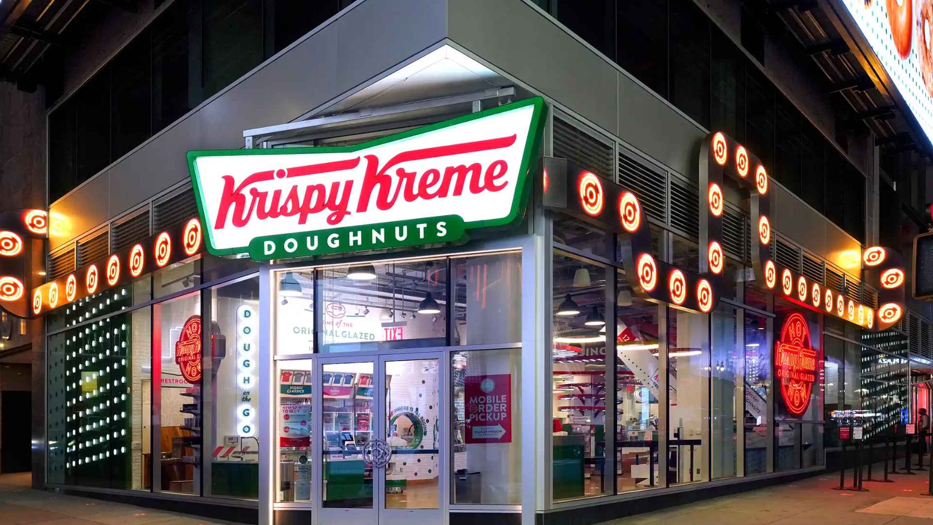 Exterior of a Krispy Kreme store promoting free Original Glazed doughnuts and patriotic flavors for July 4
