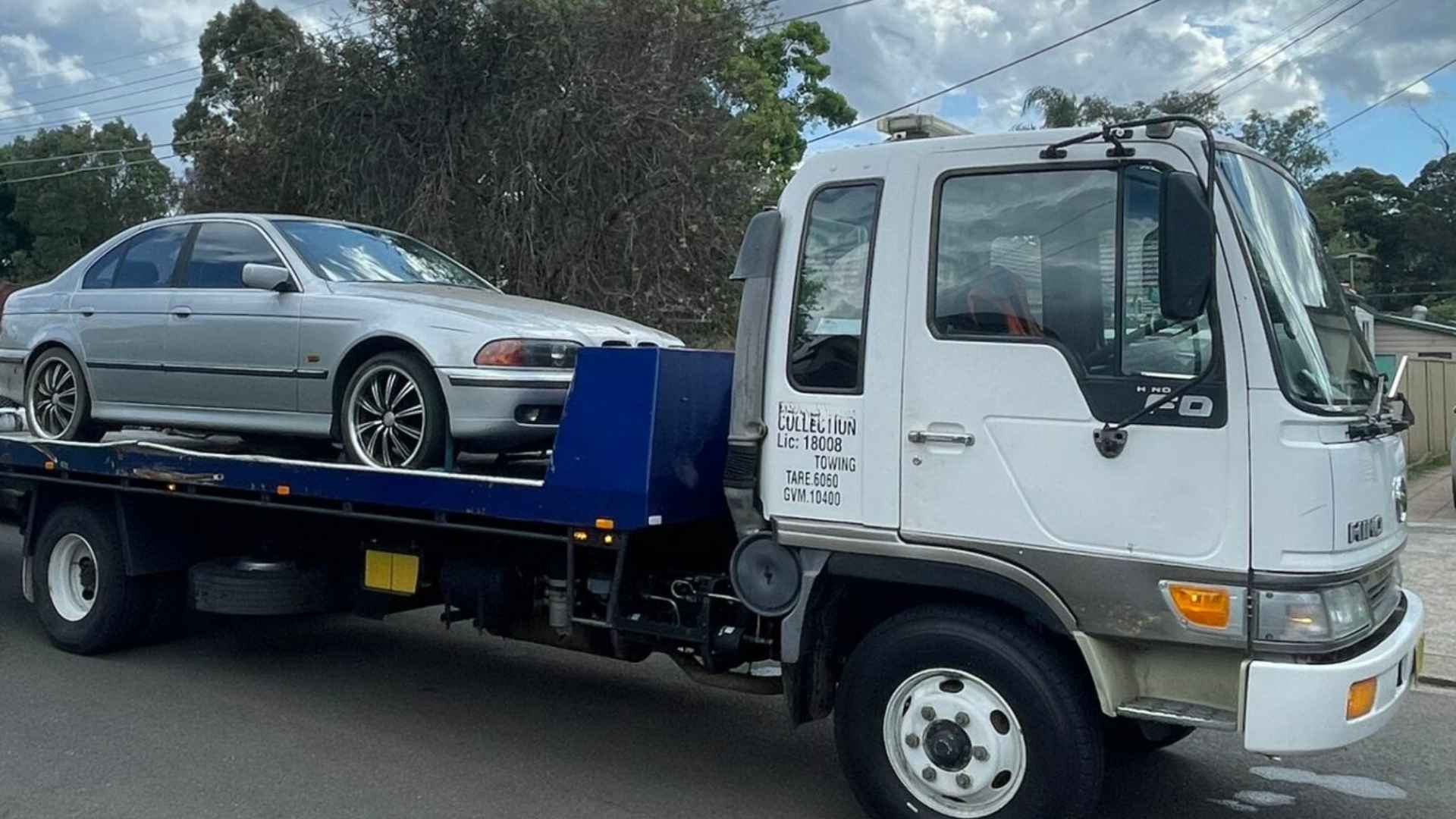BMW sedan being towed on flatbed truck due to mechanical breakdown