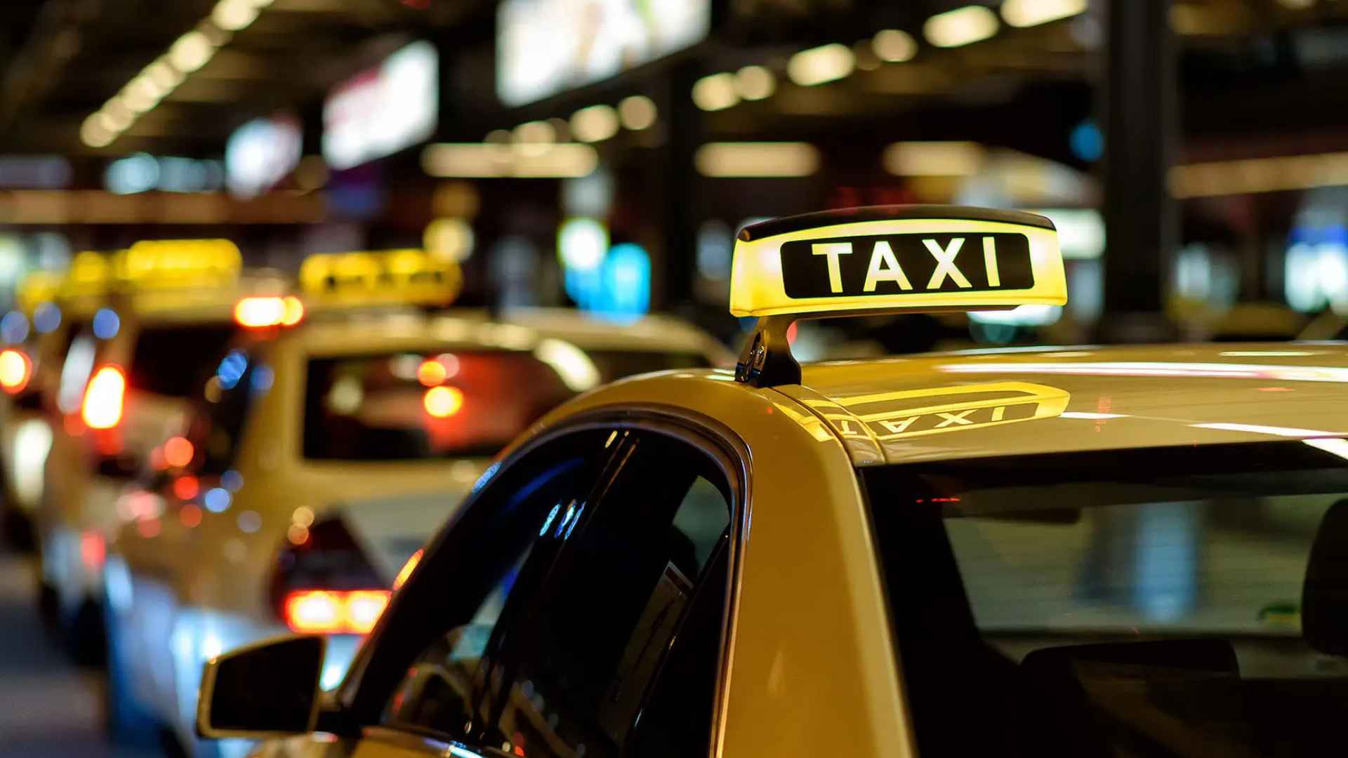 Yellow taxi roof sign in North Carolina traffic, symbolizing Uber and cab fares rising 1.5 % under the new state tax taking effect July 1.