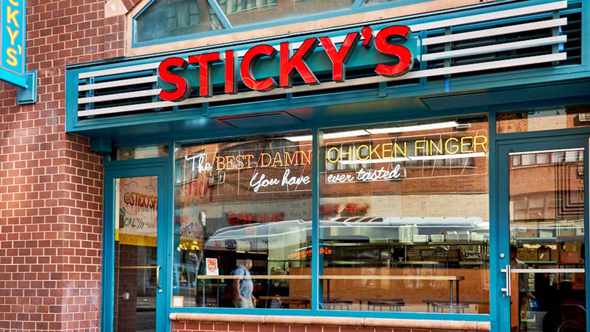Sticky's fried chicken restaurant storefront with neon slogan promoting chicken fingers