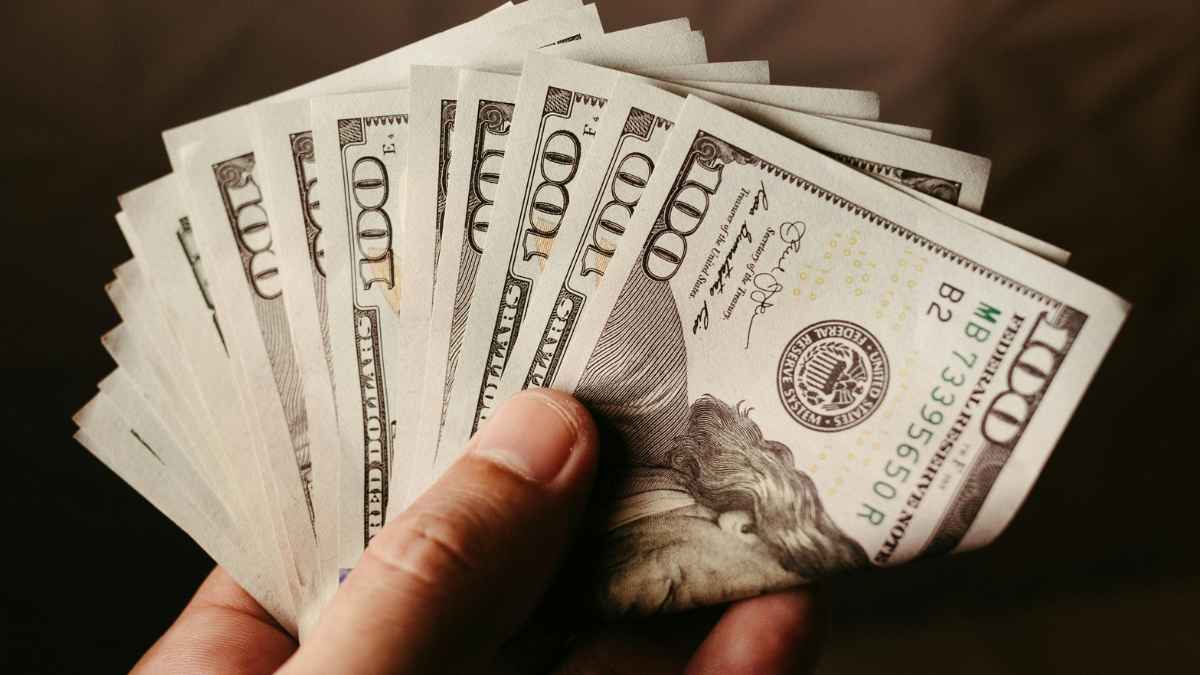Hand holding hundred-dollar bills from Prudential Financial data breach settlement