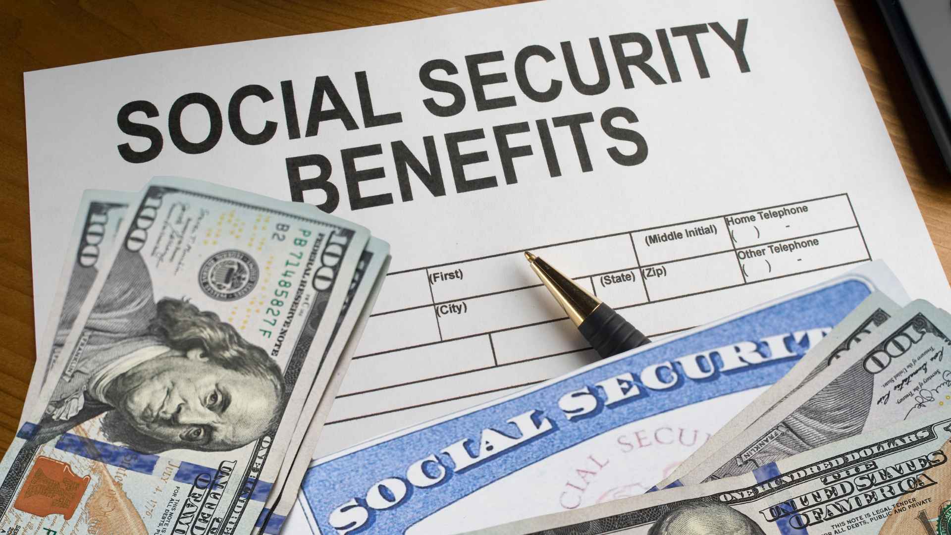 Social Security benefits form with $100 bills and pen on table