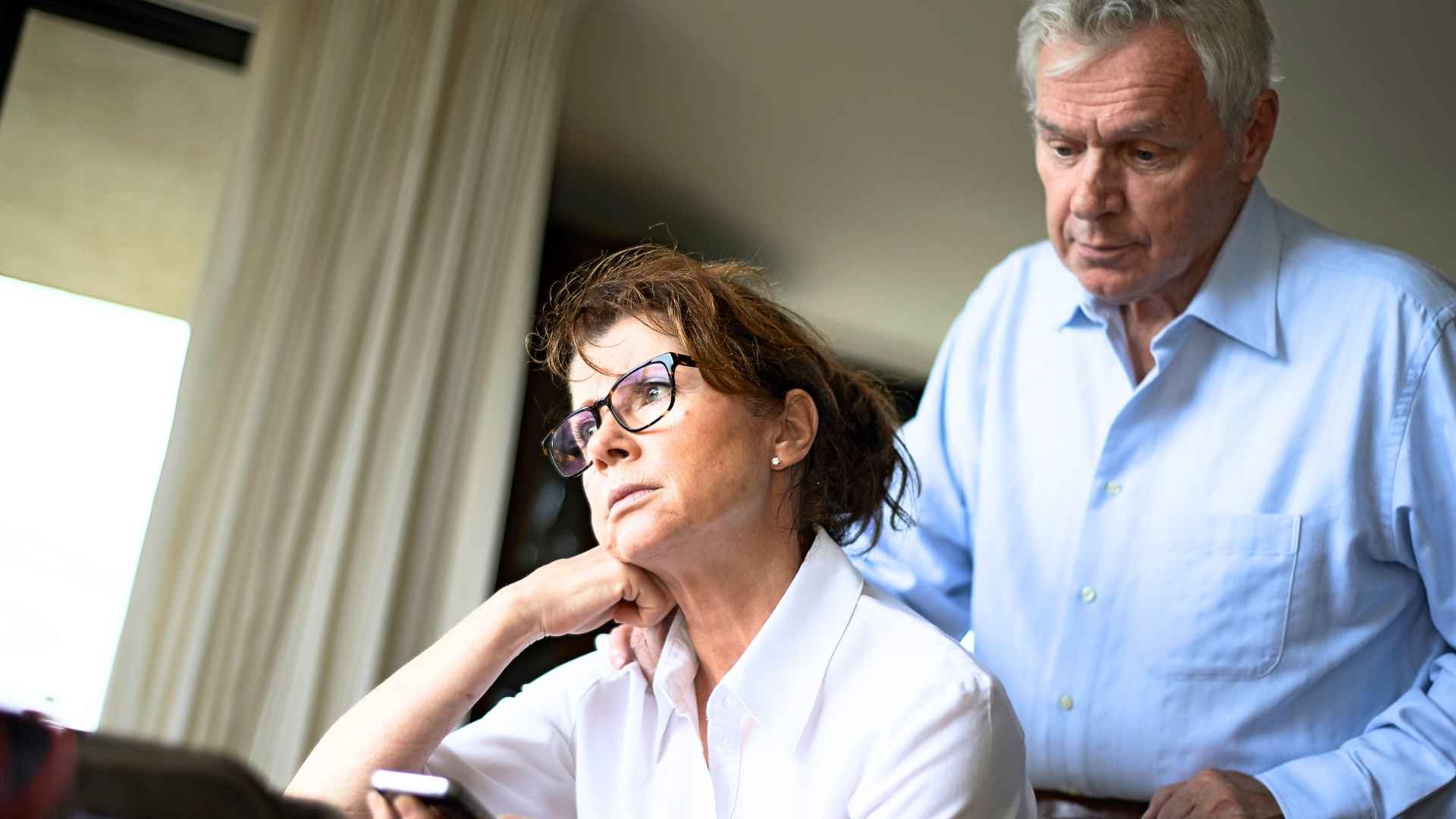 Worried retired couple reviewing Social Security benefit cuts for dual-earners starting in 2033.