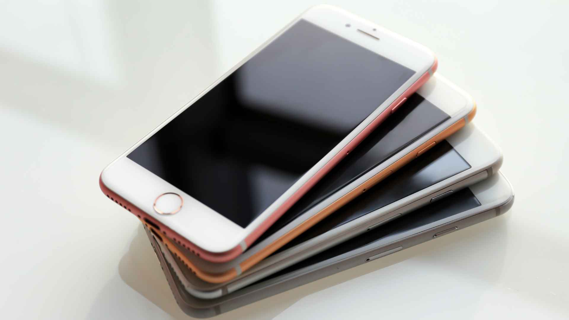 Stack of iPhones on a table, illustrating how to identify refurbished or new devices