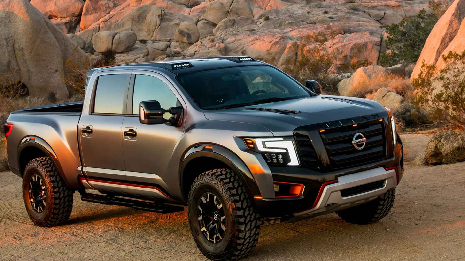 Gray Nissan Titan pickup truck with 400 horsepower, luxury features, and off-road tires parked in rugged desert landscape.