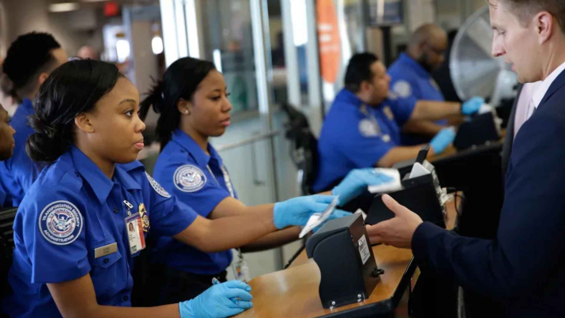 TSA agents checking passenger identification at airport security checkpoint