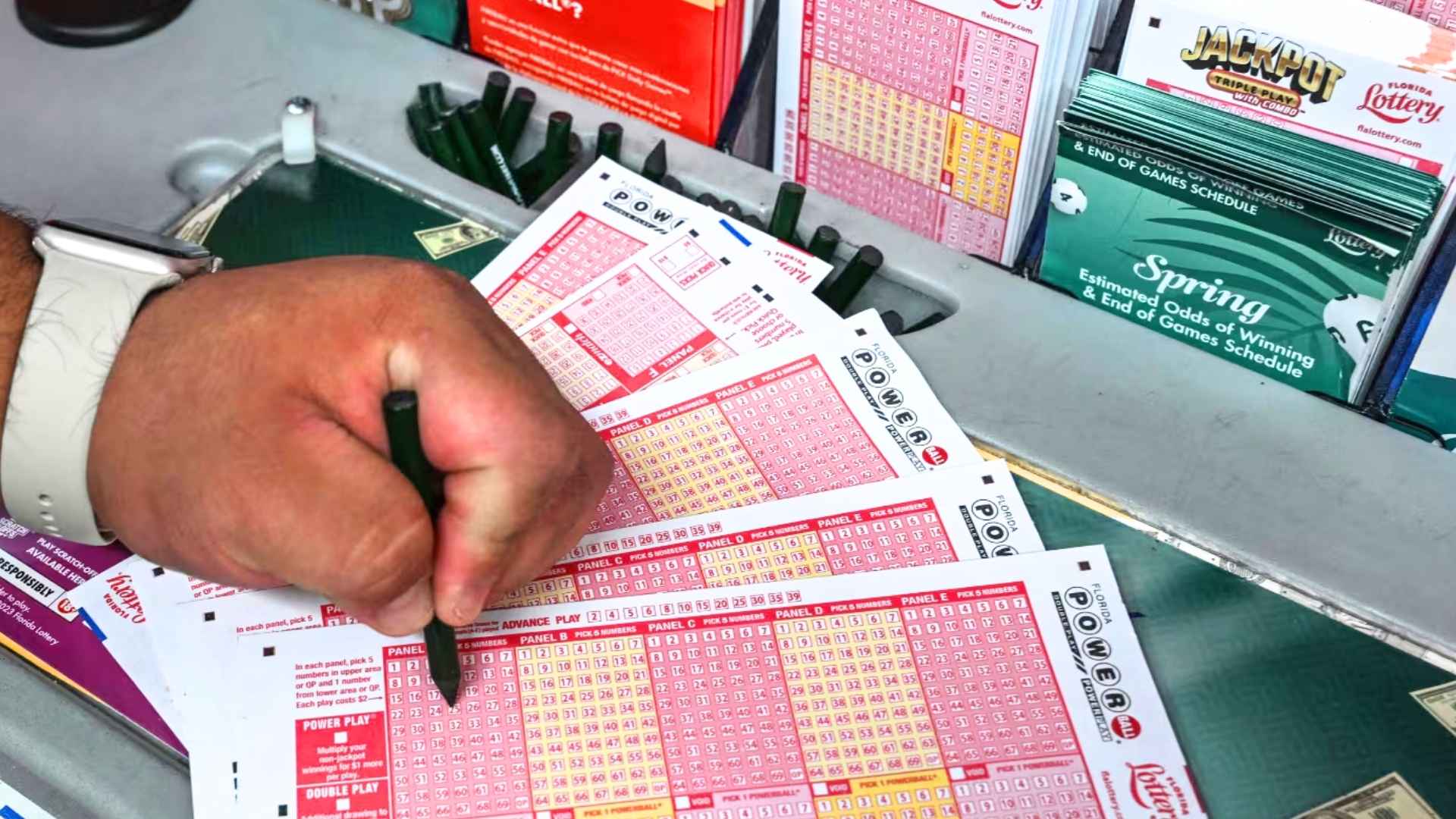 Hand marking multiple Powerball lottery tickets at a convenience-store counter