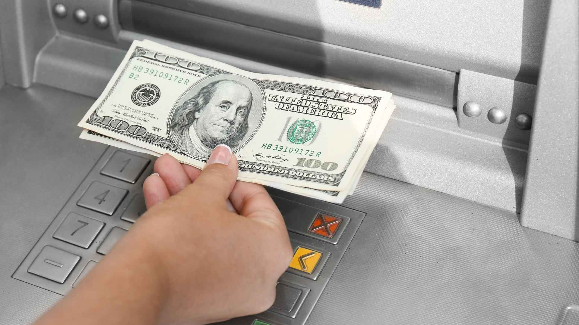 Person withdrawing 200 dollars from an ATM, subject to US federal monitoring in select border zip codes.