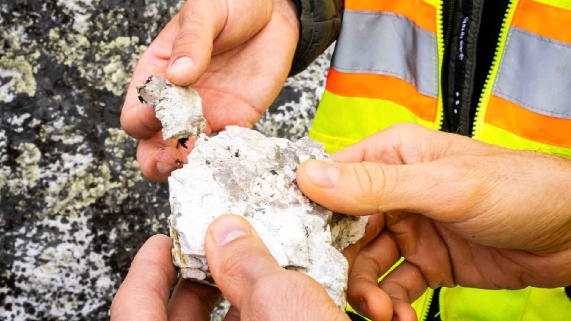 Hands holding lithium-rich rock sample from Oregon McDermitt Caldera deposit
