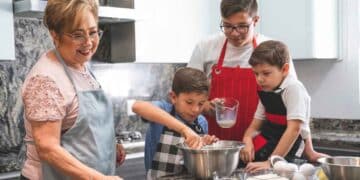 Abuela y niños cocinando juntos en la cocina, representando el rol de amas de casa y el cuidado familiar