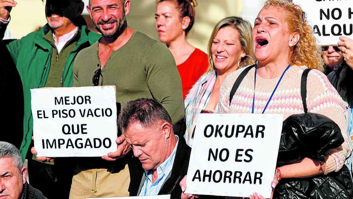 “Grupo de personas sosteniendo carteles que rechazan la okupación ilegal de viviendas en España, reclamando desalojos más rápidos.”