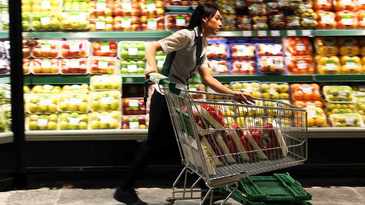 Trabajadora de El Corte Inglés empujando un carrito de compra en la sección de alimentación