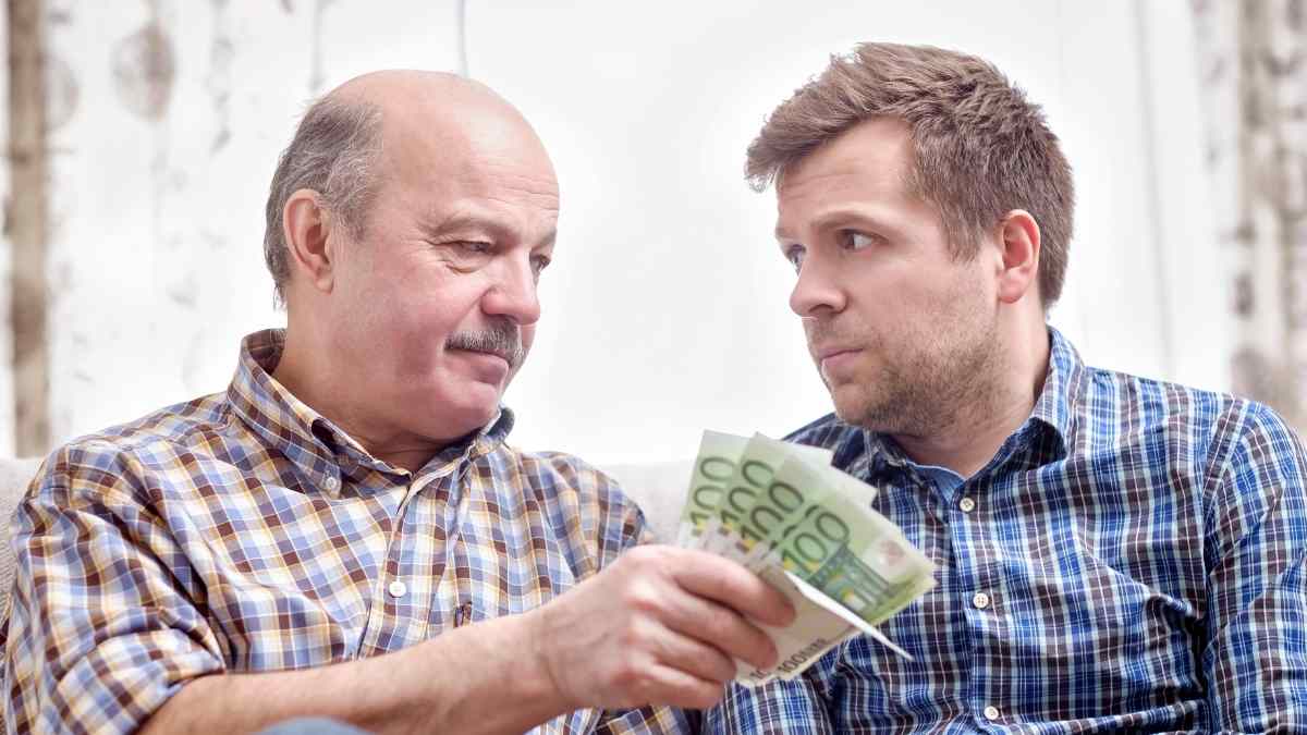 Padre entregando billetes de euro a su hijo como donación para evitar problemas con Hacienda